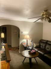Living room featuring carpet floors, arched walkways, and a ceiling fan. APT 2