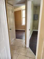 Corridor with light tile patterned floors and electric panel. APT 3