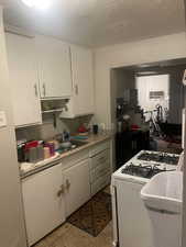 Kitchen with white cabinetry, white gas range oven, light countertops, and light tile patterned flooring. APT 2