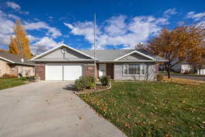 Single story home featuring brick and stucco siding, driveway, a garage, and a front yard