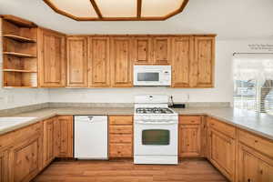 Kitchen featuring white appliances, open shelves, light countertops, and light wood-style flooring