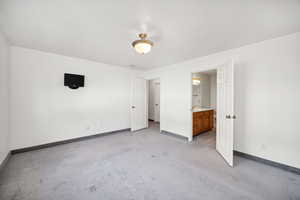 Primary bedroom featuring light carpet and ensuite bathroom
