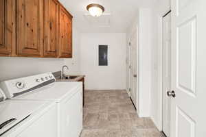 Washroom featuring washing machine and clothes dryer, cabinet space, and electric panel
