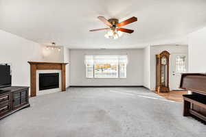 Unfurnished living room with light colored carpet, a fireplace, and a ceiling fan