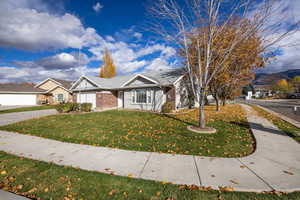 View of front of house with brick siding, a front lawn, driveway, and an attached garage