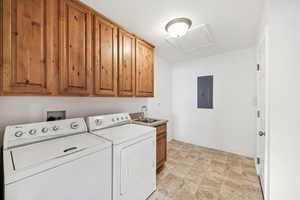 Laundry room featuring cabinet space, electric panel, washing machine and dryer, and attic access