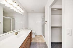 Bathroom featuring a walk in closet, vanity, and a stall shower