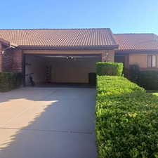 View of front of house featuring brick siding, driveway, a garage, and a tile roof