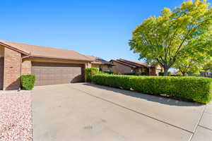 Ranch-style house featuring brick siding, concrete driveway, a tiled roof, and an attached garage
