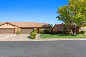 Single story home featuring a tile roof, a front lawn, driveway, stucco siding, and an attached garage