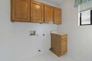 Washroom with hookup for a washing machine, cabinet space, gas dryer hookup, and hookup for an electric dryer