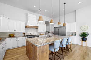 Kitchen featuring tasteful backsplash, white cabinets, a breakfast bar, brown cabinetry, and a towering ceiling