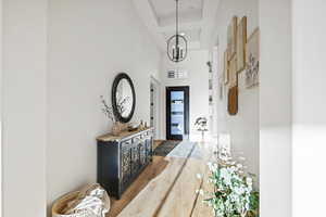 Hallway featuring dark wood-type flooring, a chandelier, a tray ceiling, and a high ceiling