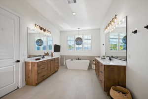 Full bathroom featuring two vanities, a freestanding tub, and light tile patterned flooring