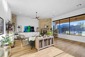 Living area featuring ceiling fan, a fireplace, light wood-style flooring, and recessed lighting