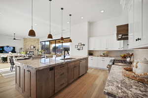 Kitchen featuring a stone fireplace, white cabinets, dark stone counters, tasteful backsplash, and recessed lighting