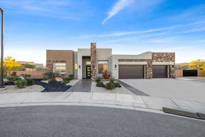 View of front facade featuring stone siding, concrete driveway, stucco siding, and a garage