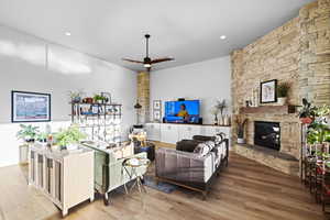 Living area with light wood-style floors, ceiling fan, a fireplace, and recessed lighting