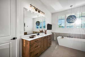 Bathroom featuring vanity, a soaking tub, and light tile patterned floors