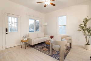 Living room featuring healthy amount of natural light, light wood-type flooring, and ceiling fan