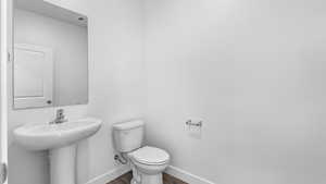 Half bathroom featuring toilet and dark wood-style flooring