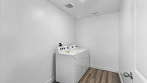 Laundry room with dark wood-style flooring and washer and clothes dryer