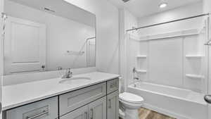 Bathroom featuring vanity, shower / bath combination, and light wood-style floors