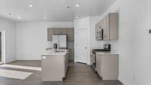 Kitchen with stainless steel appliances, an island with sink, dark wood finished floors, recessed lighting, and gray cabinetry