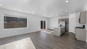 Kitchen featuring gray cabinets, open floor plan, a kitchen island with sink, dark wood-type flooring, and recessed lighting