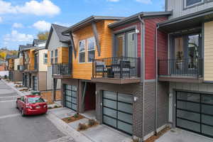 View of home's exterior with a residential view, a balcony, an attached garage, concrete driveway, and brick siding