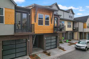 Contemporary home featuring a balcony, brick siding, an attached garage, and driveway