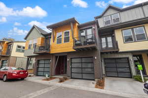 Contemporary house featuring board and batten siding, brick siding, a balcony, a garage, and driveway