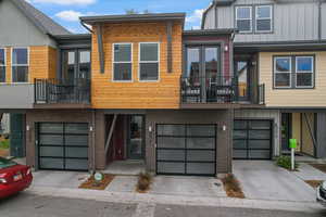 Contemporary home with a balcony, driveway, a garage, and brick siding