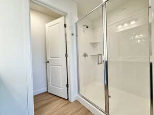 Full bathroom featuring light wood finished floors and a stall shower