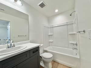 Bathroom with bathtub / shower combination, vanity, and light wood-type flooring