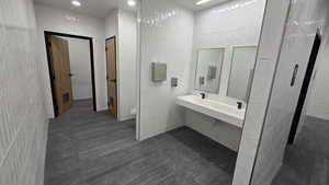 Bathroom with tile walls, vanity, recessed lighting, and dark tile patterned flooring