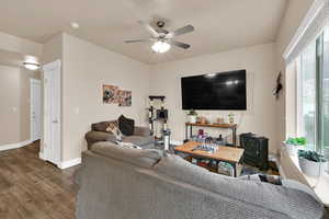 Living area with wood finished floors, ceiling fan, and a wood stove