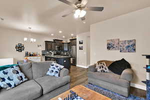 Living room featuring recessed lighting, a chandelier, dark wood-style flooring, and a ceiling fan