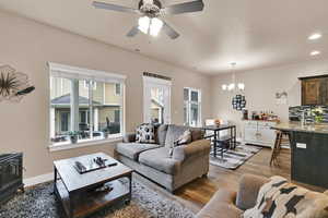 Living area with a wood stove, dark wood-style floors, a chandelier, a ceiling fan, and recessed lighting