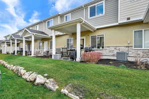 Rear view of property featuring a patio, a yard, stucco siding, and stone siding