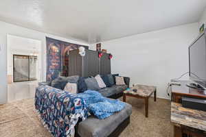 Carpeted living area with a chandelier and a textured ceiling