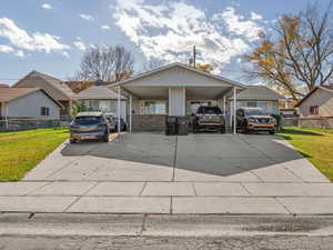 View of front facade featuring concrete driveway and a carport