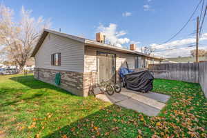 Back of house featuring a fenced backyard, brick siding, and a patio area