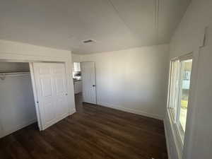 Unfurnished bedroom with dark wood-type flooring and a closet