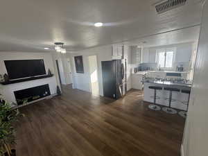 Kitchen with white cabinetry, a kitchen bar, stainless steel appliances, open floor plan, and dark wood-style floors