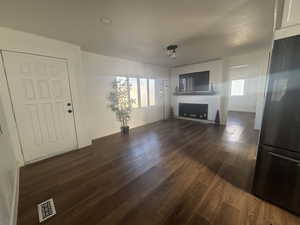 Unfurnished living room featuring dark wood-type flooring and baseboards