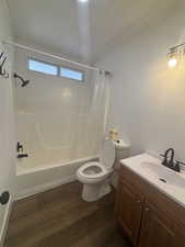 Bathroom featuring dark wood-style floors, shower / bathtub combination with curtain, and vanity