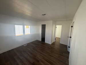 Spare room featuring dark wood-type flooring and a textured ceiling