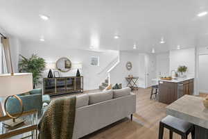 Living area with light wood finished floors, stairway, and recessed lighting