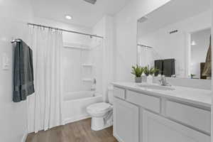 Bathroom featuring light wood-style flooring, shower / bath combo with shower curtain, and vanity